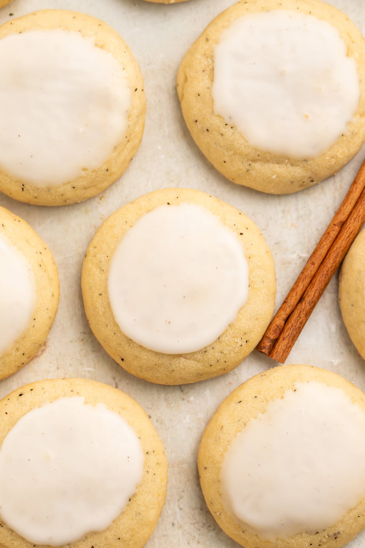 Close-up of a chai cookie made from Taylor Swift's recipe surrounded by other cookies flat on parchment paper, next to a cinnamon stick.