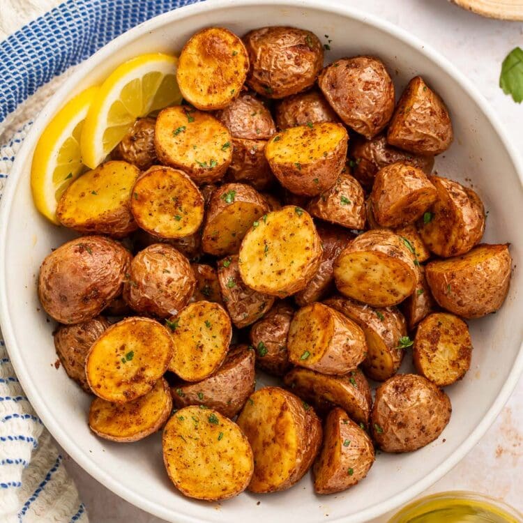 A bowl of air fryer red potatoes with 2 lemon slices.
