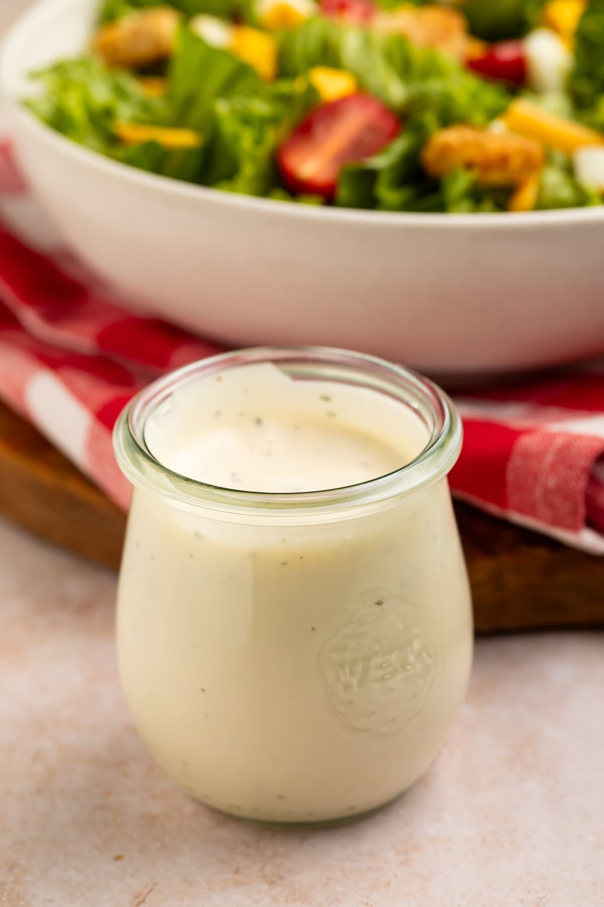 jar of ranch dressing with a tomato and lettuce salad just visible in the background. 