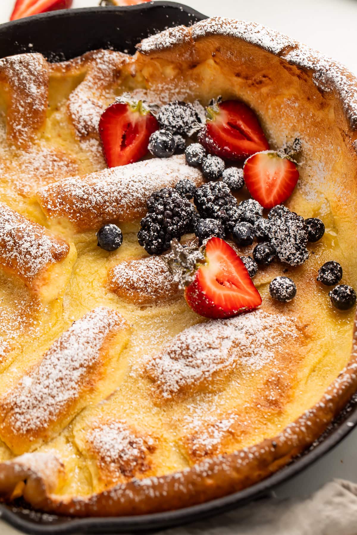 Pillowy dutch baby pancake finished with powdered sugar and fresh berries.