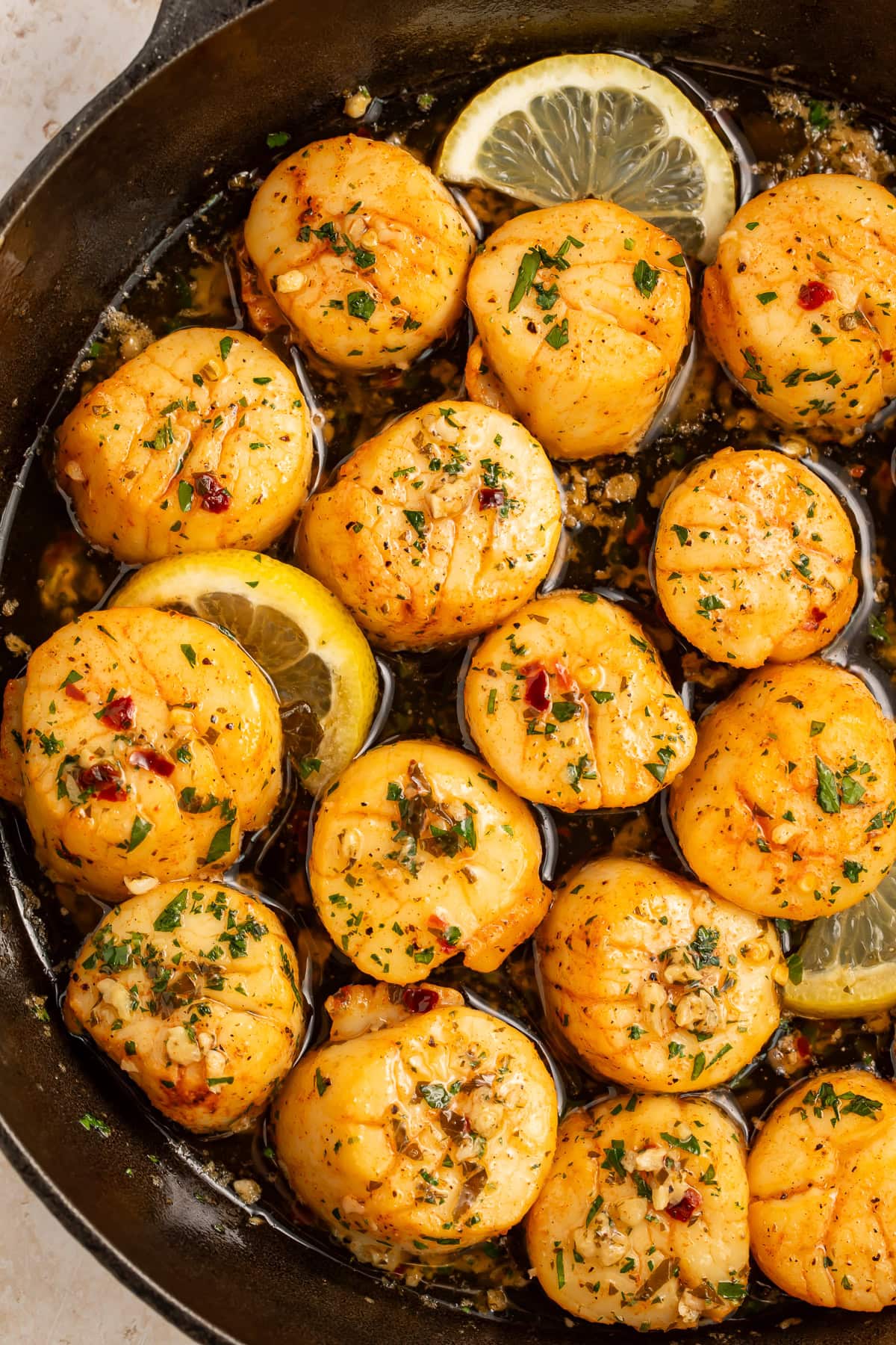 Scallops with a lemon, garlic and herb butter in a cast iron skillet.