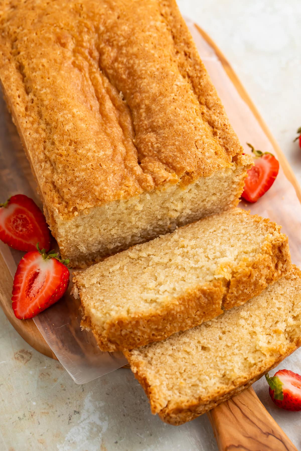 Top down picture of a sliced pound cake on a wooden board.
