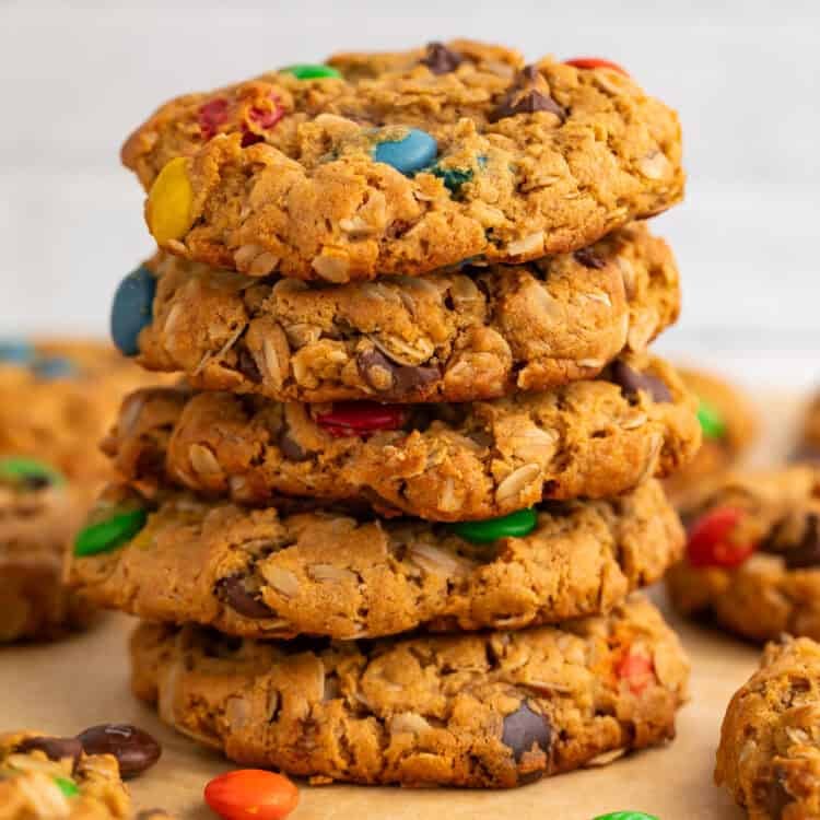Stack of monster cookies on a piece of baking parchment.