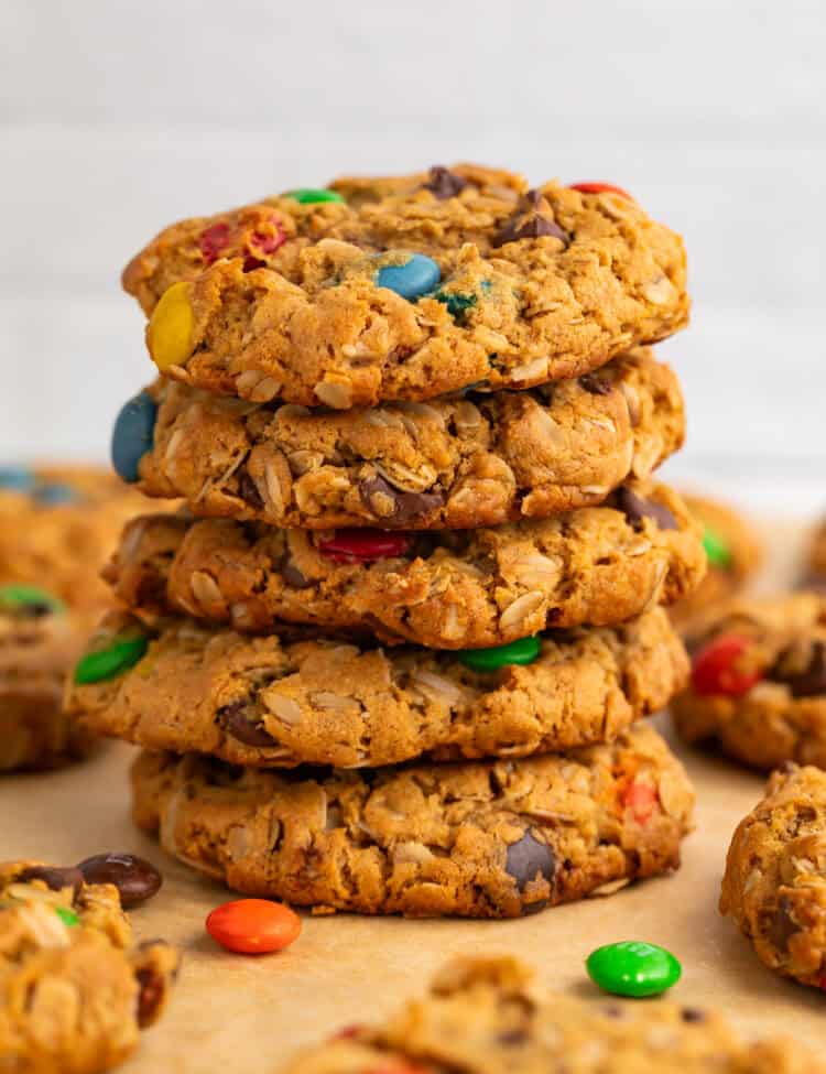 Stack of monster cookies on a piece of baking parchment.