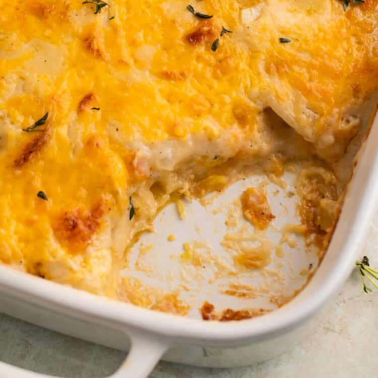 Close up of a dish of scalloped potatoes with a spoonful taken out to show the middle.