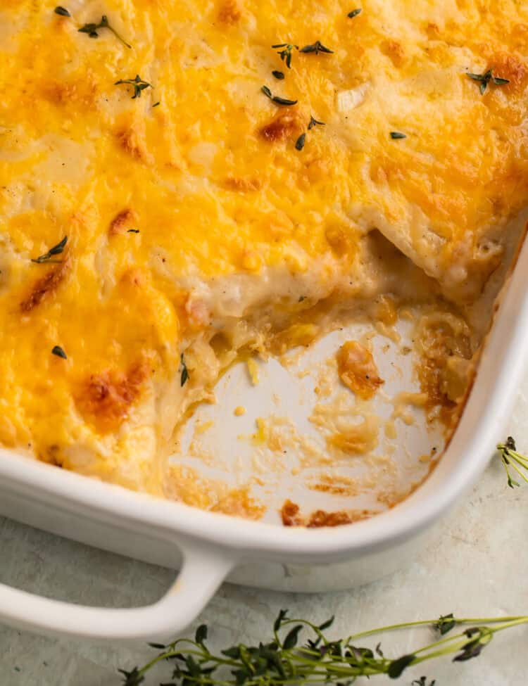 Close up of a dish of scalloped potatoes with a spoonful taken out to show the middle.