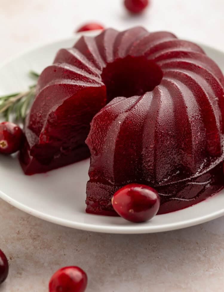 Jellied cranberry sauce made in a bundt pan on a white plate with a slice taken out of the side.