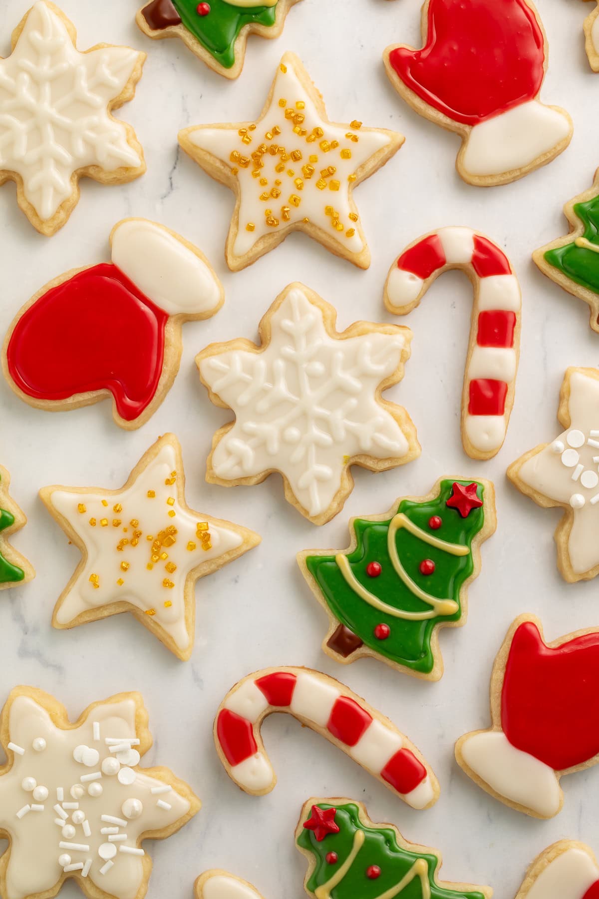 Top down view of vegan decorated Christmas cookies with tars, snowflakes, trees, candy canes and gloves.