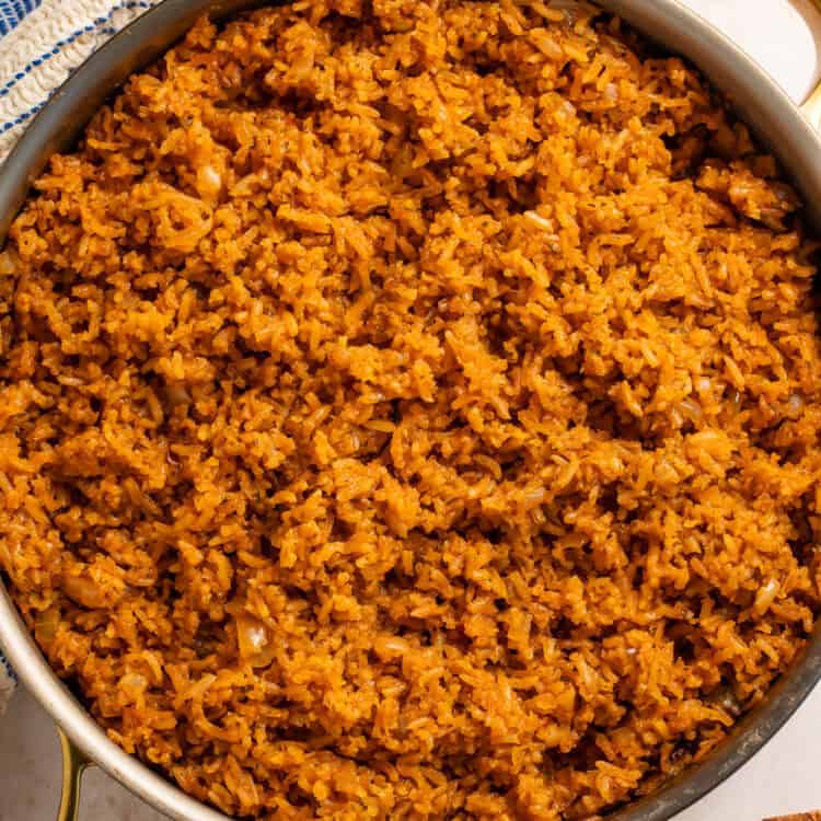 Pan of seasoned rice with a blue and white kitchen towel on one side.