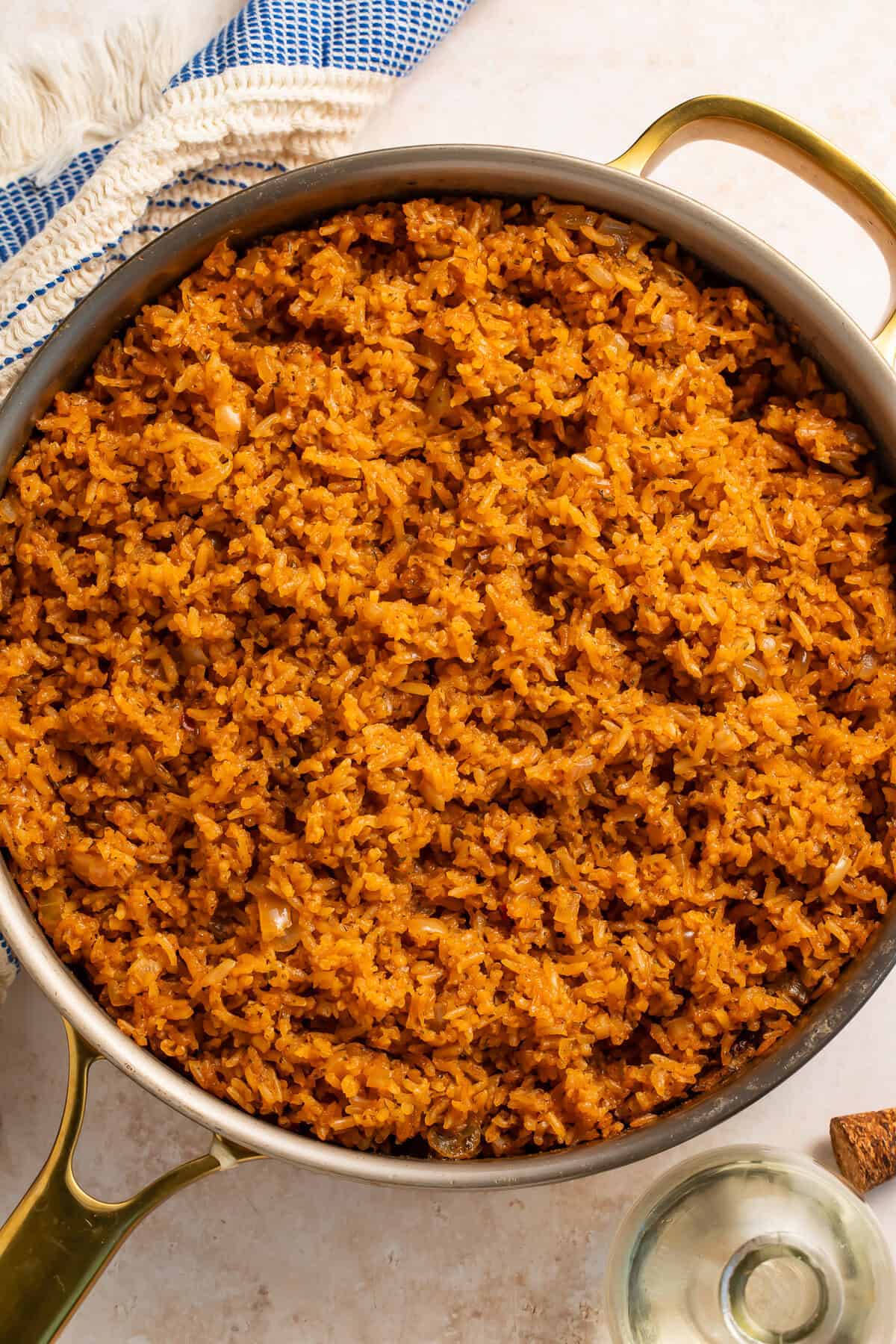 Pan of seasoned rice with a blue and white kitchen towel on one side.