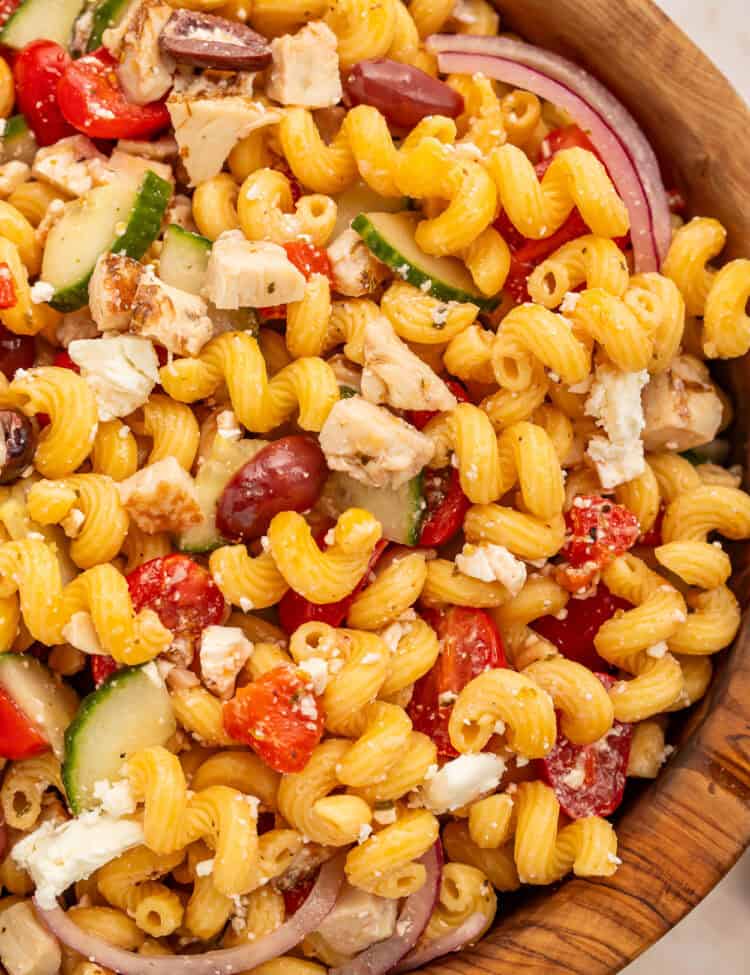 Close up of pasta salad with chicken, onions, olives and feta