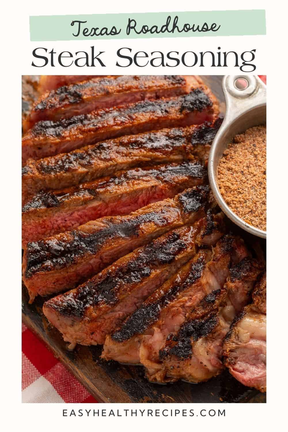 Close up of a sliced grilled steak with a metal pot of seasoning off to one side.