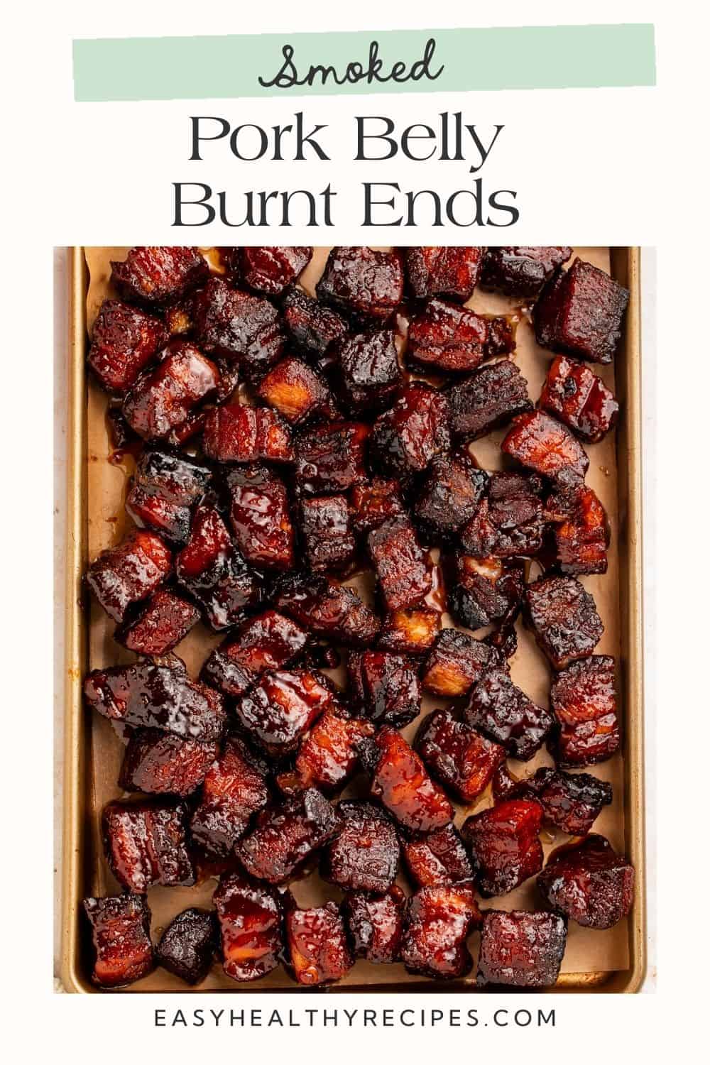 Close up of a sheet pan of pork belly burnt ends with a Pinterest-optimised text frame overlay.