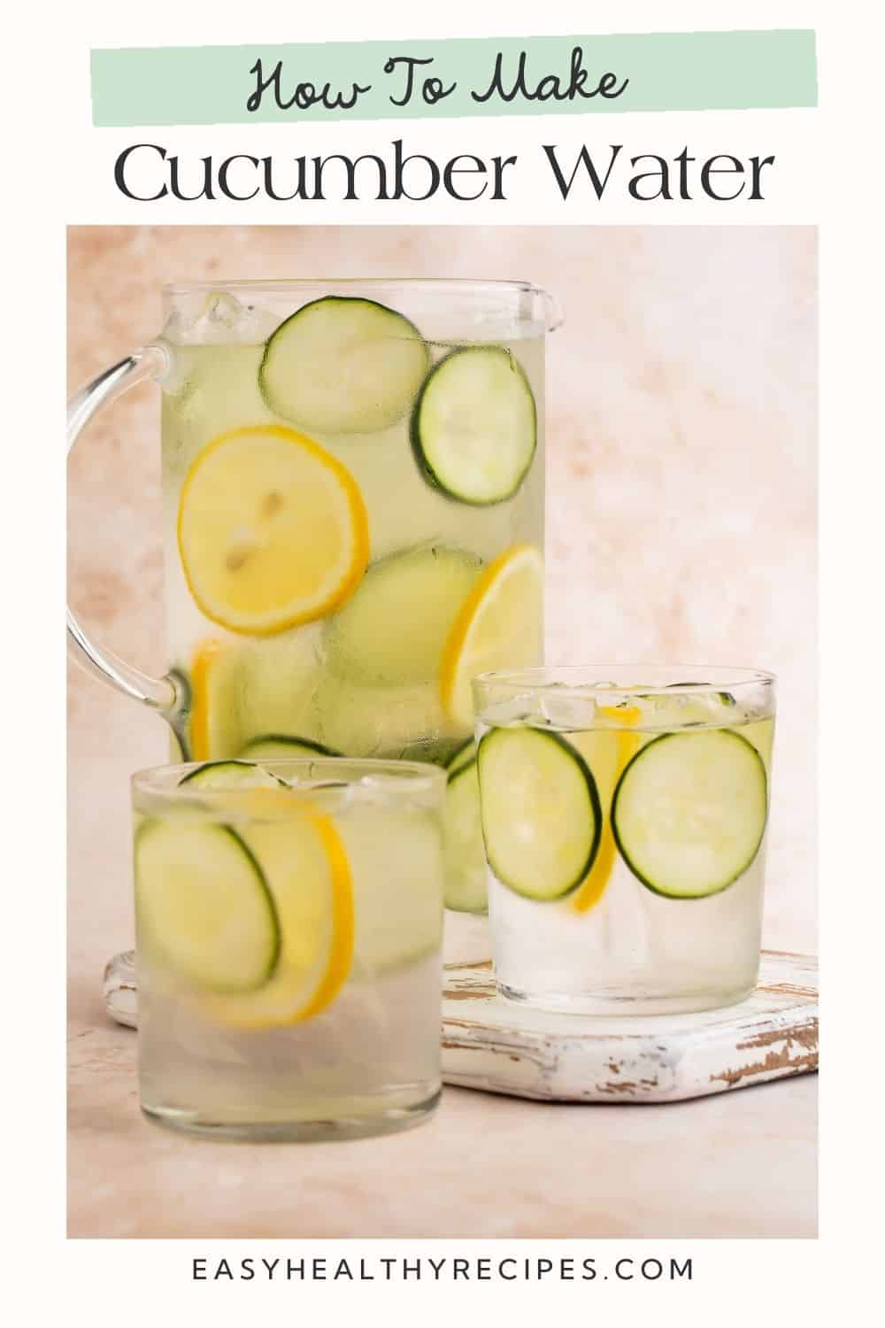 Two glasses and a jug of infused cucumber water filled with lemon and cucumber wheels.