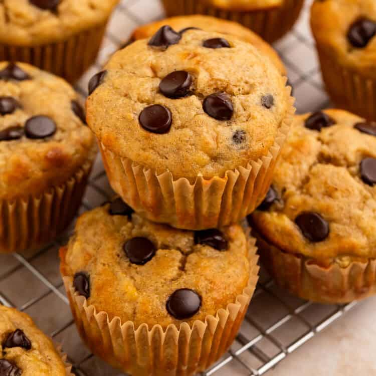 Banana muffins with chocolate chips stacked on a wire rack.