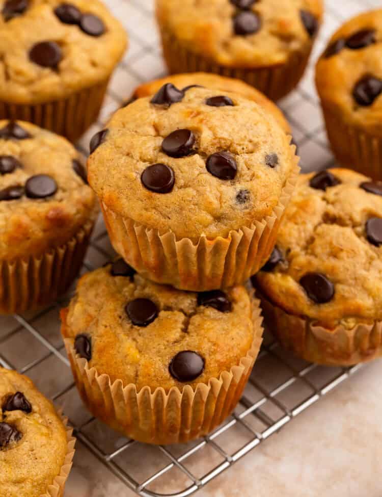 Banana muffins with chocolate chips stacked on a wire rack.