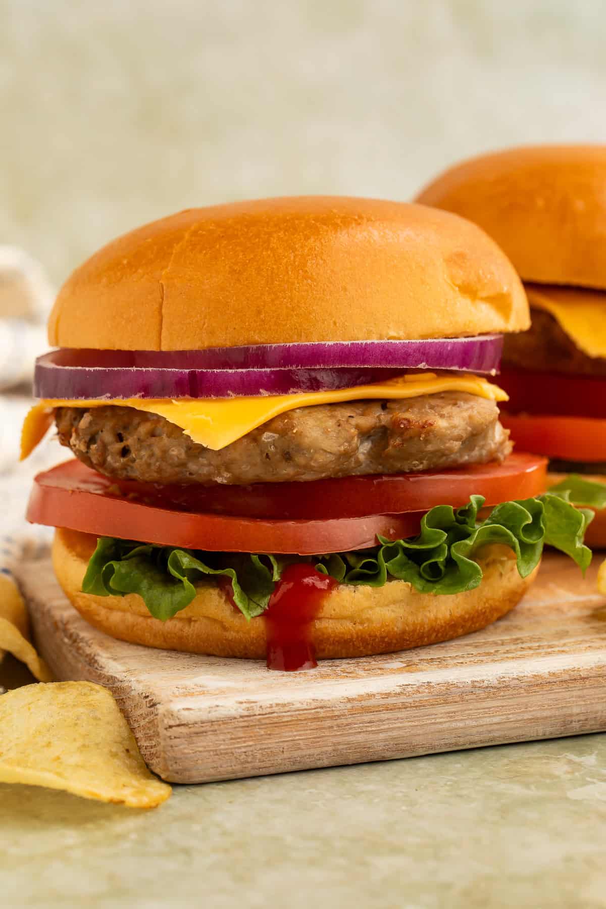 Close-up of an air fryer turkey burger with cheddar cheese, tomato, lettuce, and red onion on a brioche bun