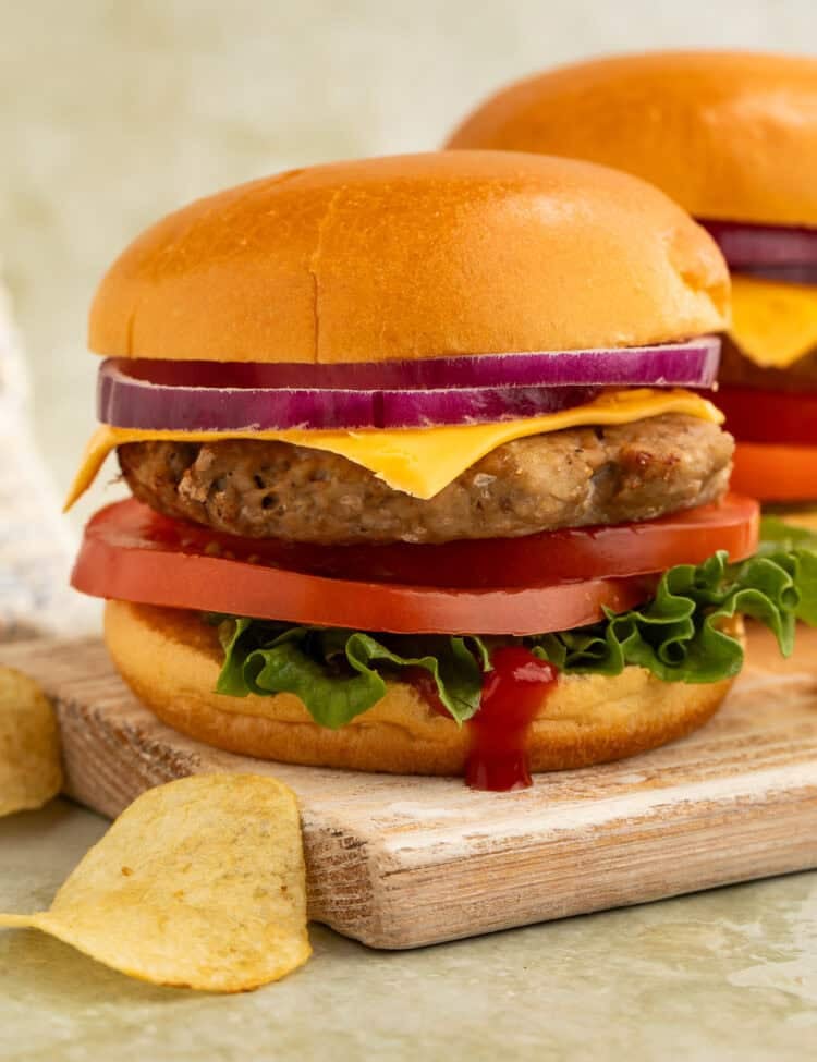 Air fryer turkey burger with cheddar cheese, lettuce, tomato, and red onion served on a brioche bun