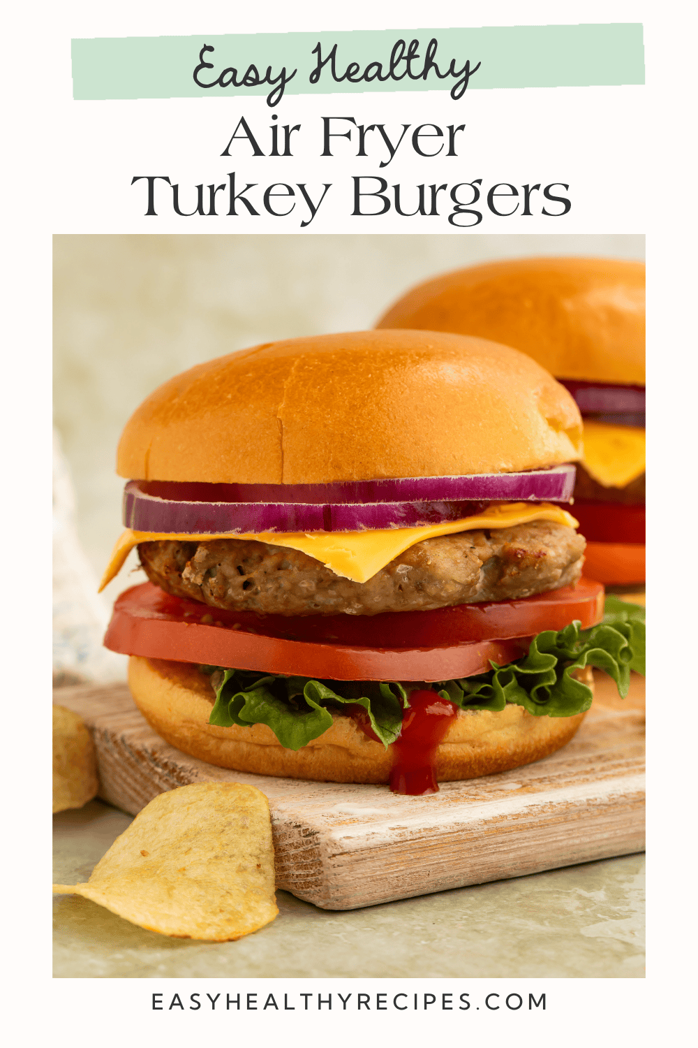 A tall, loaded air fryer turkey burger with cheddar cheese, red onion, tomato, and lettuce on a golden toasted bun, with ketchup dripping down the side