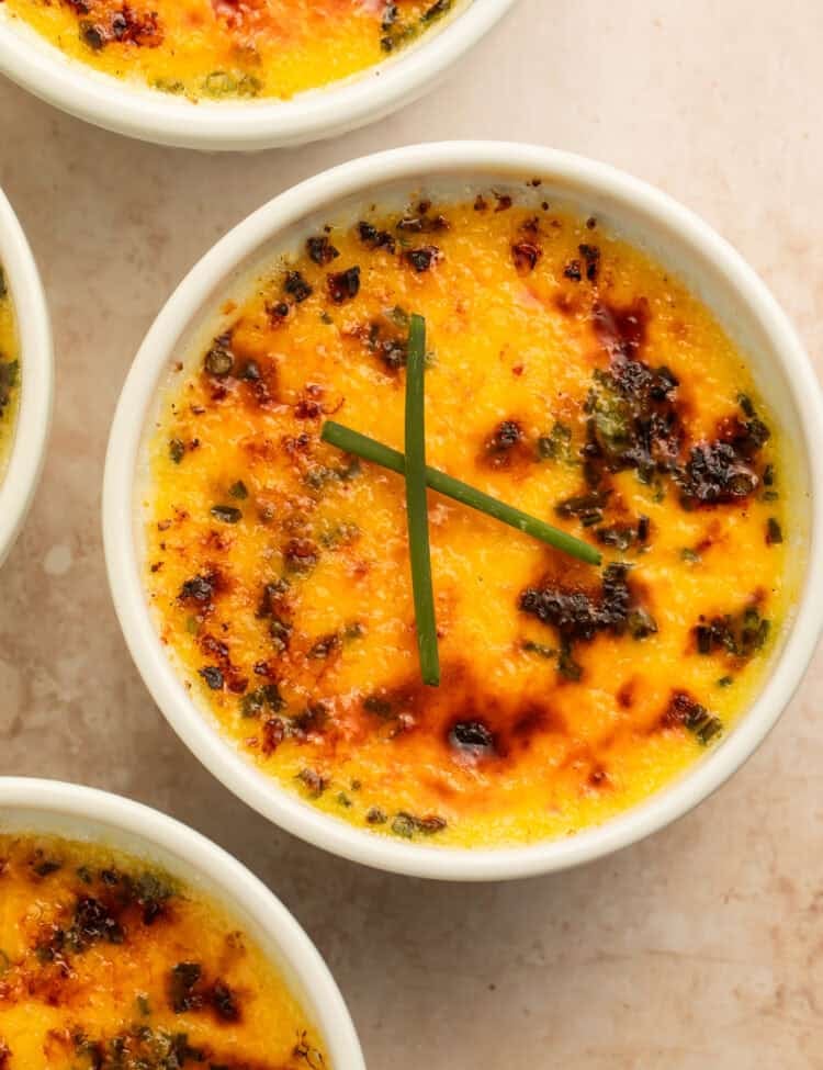 Baked crab brulee ramekins with golden browned tops and chive garnish