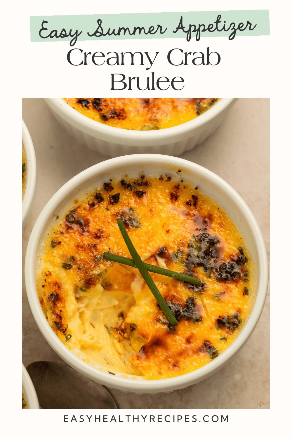 Overhead view of crab brûlée in white ramekin with golden caramelized crust and chive garnish