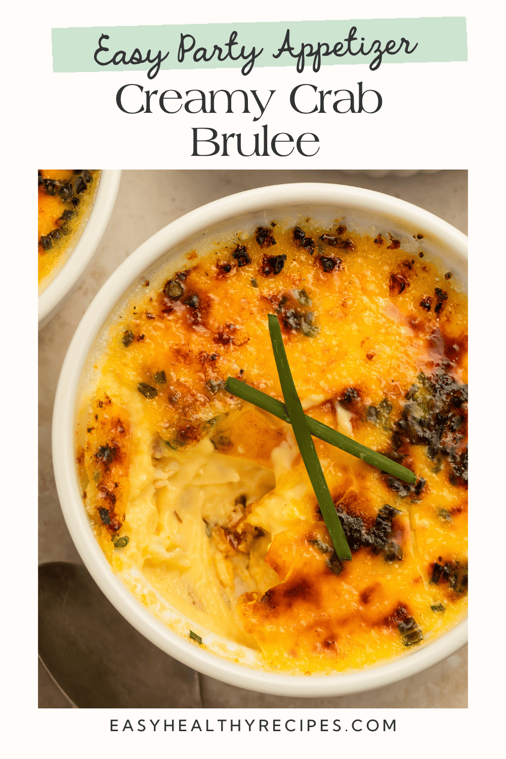 Close-up overhead of crab brûlée ramekin with deeply caramelized amber crust and crossed chive stems