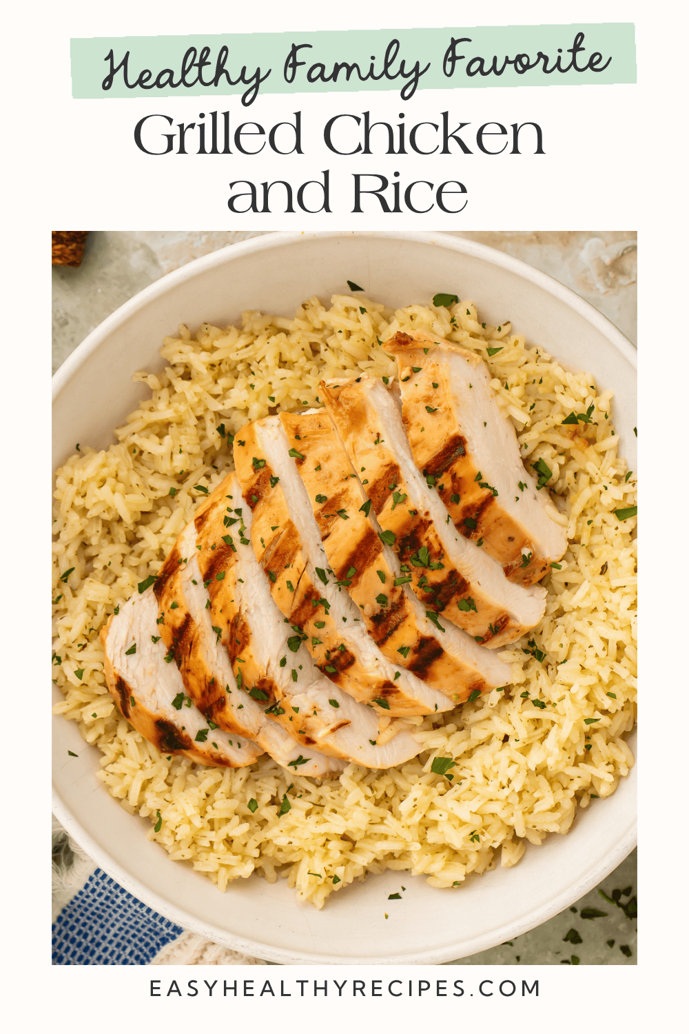 Overhead close-up of sliced grilled chicken with grill marks over buttery seasoned rice in a white bowl