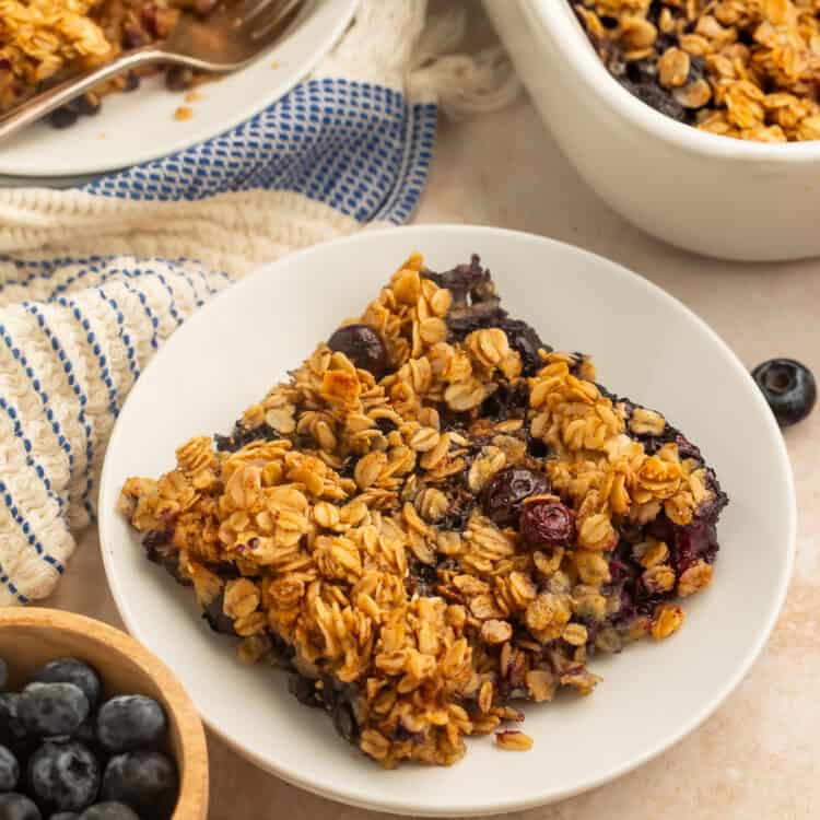 Slice of blueberry baked oatmeal with oat topping served in a white bowl