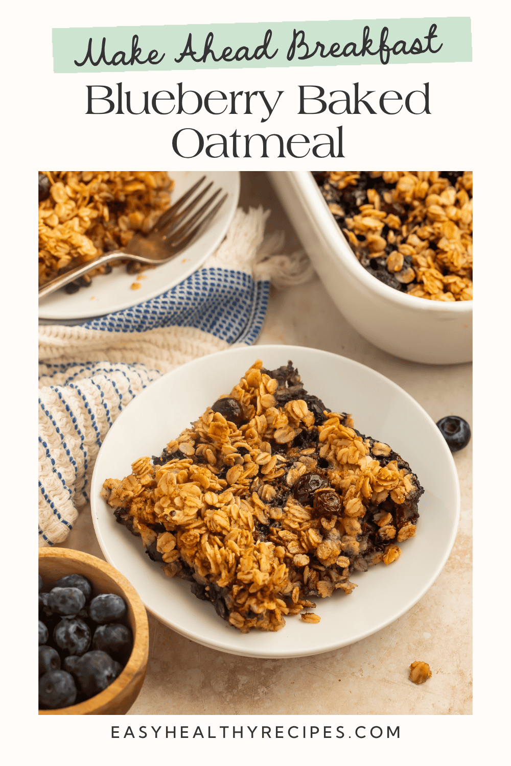 Angled overhead view of a slice of blueberry baked oatmeal on a white plate with a wooden bowl of fresh blueberries