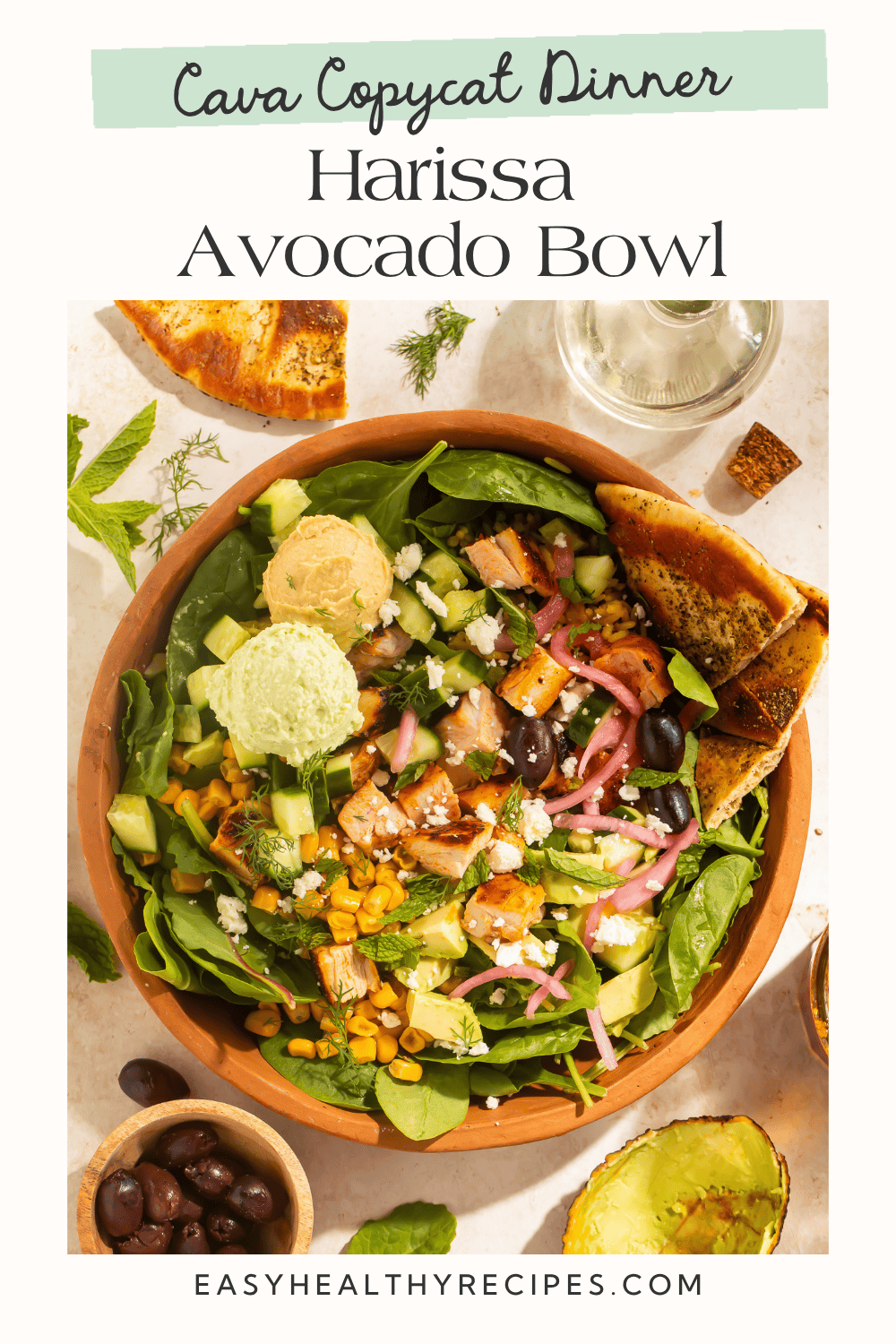 Top-down view of Cava copycat harissa avocado bowl with chicken, greens, corn, avocado, and pita wedges