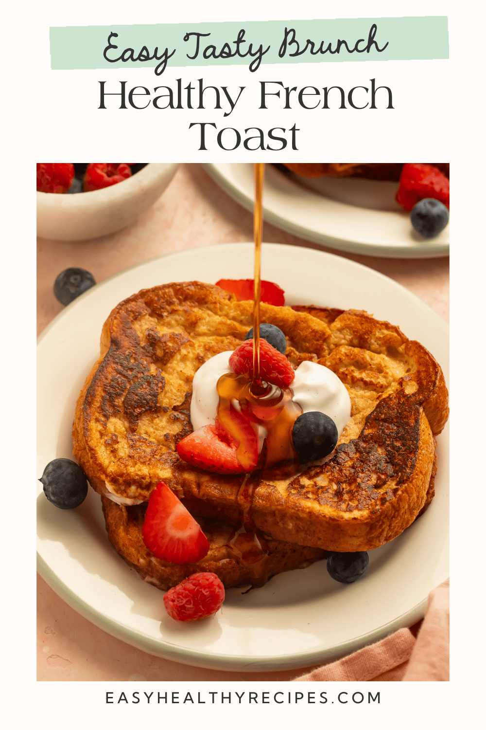 Healthy French toast on a cream plate with maple syrup being poured over Greek yogurt and berries