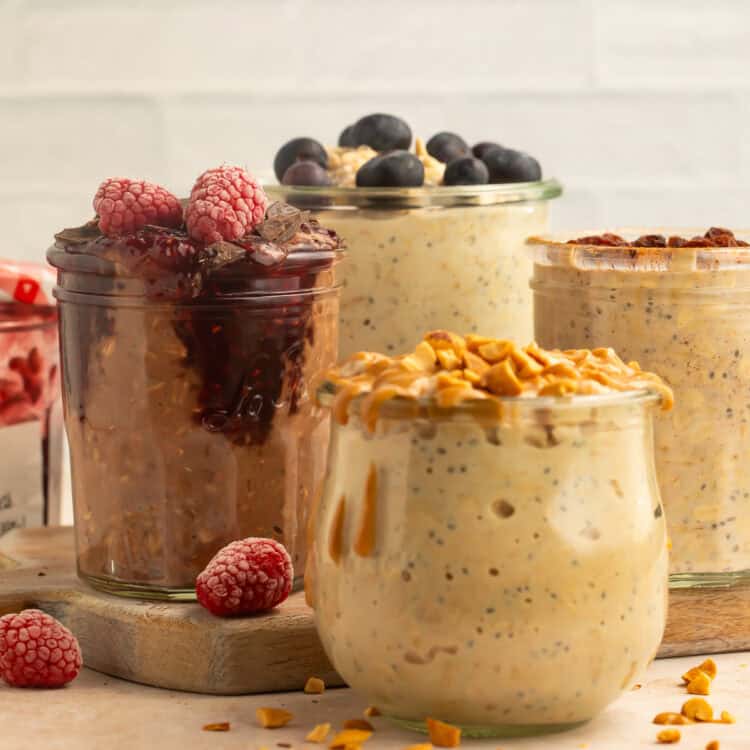 Mixed vegan overnight oats flavors in glass jars with fruit, nuts, and jam toppings