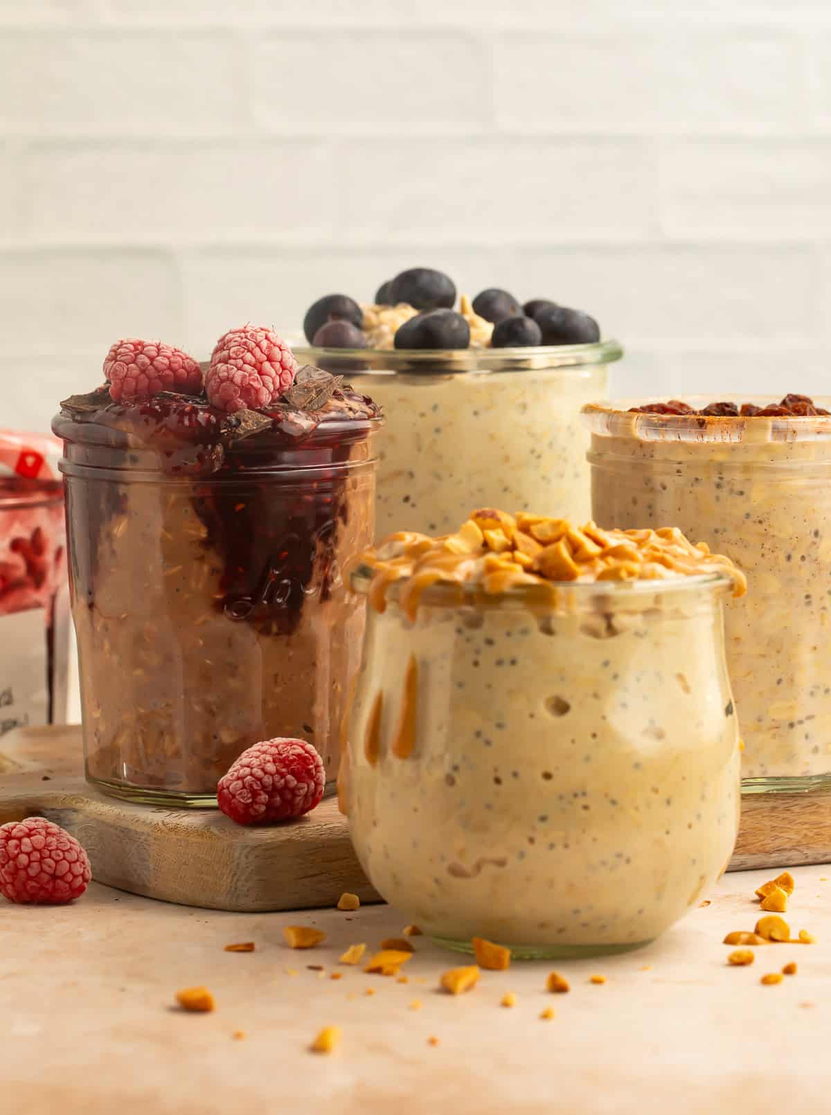 Mixed vegan overnight oats flavors in glass jars with fruit, nuts, and jam toppings