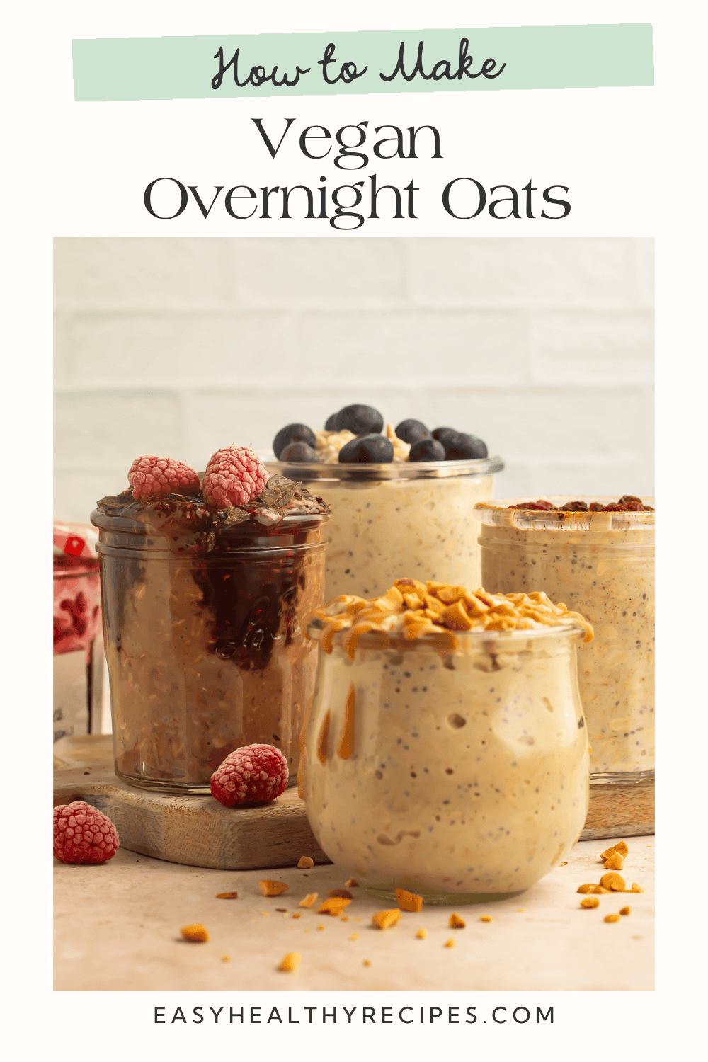 Four jars of vegan overnight oats with peanut butter, blueberries, chocolate raspberries, and raisins on a wooden board