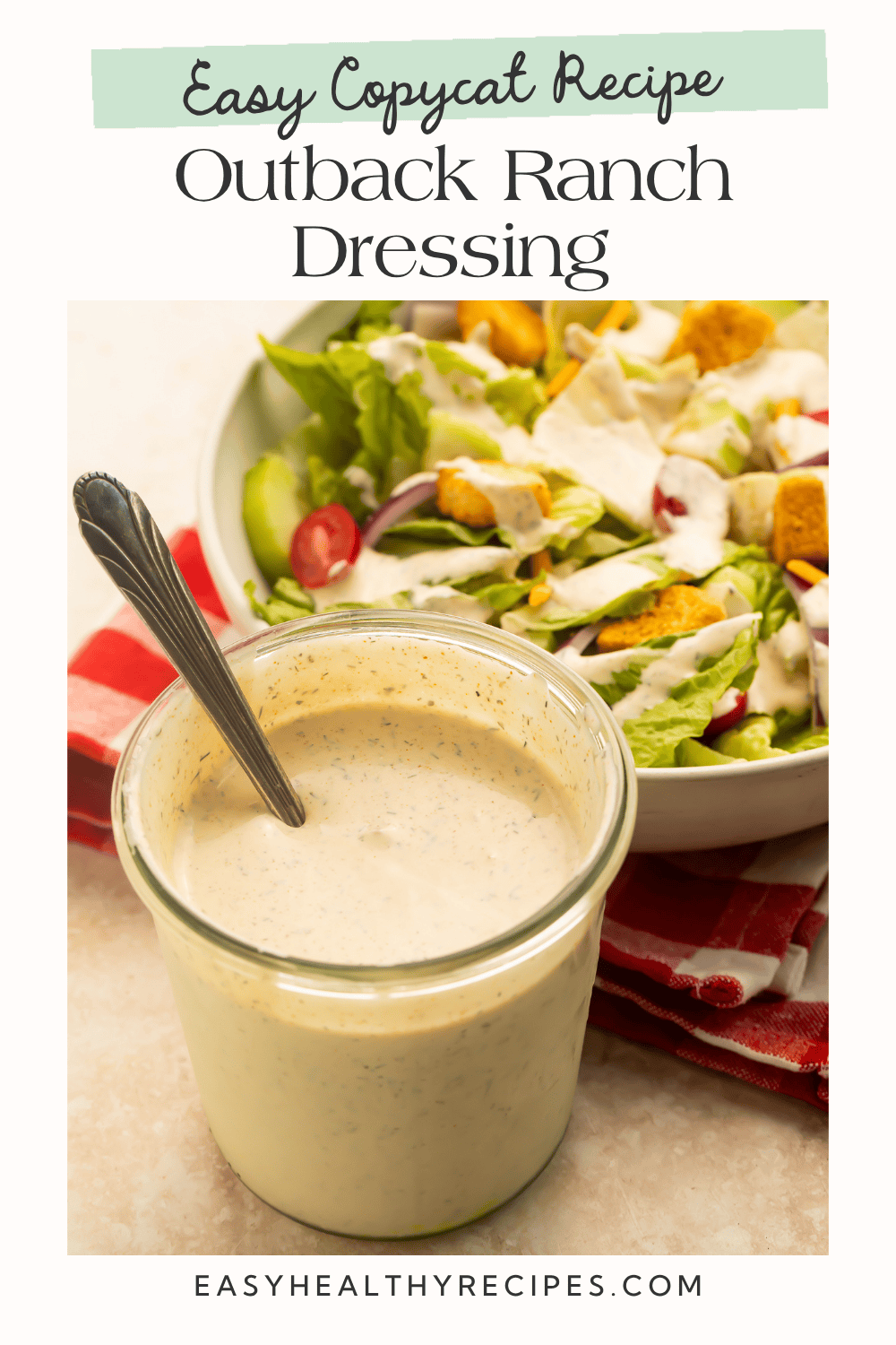 Glass jar of homemade Outback copycat ranch dressing with a spoon beside a garden salad