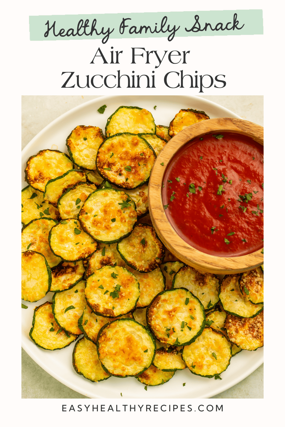 Plate of crispy parmesan air fryer zucchini chips served with a bowl of marinara dipping sauce.
