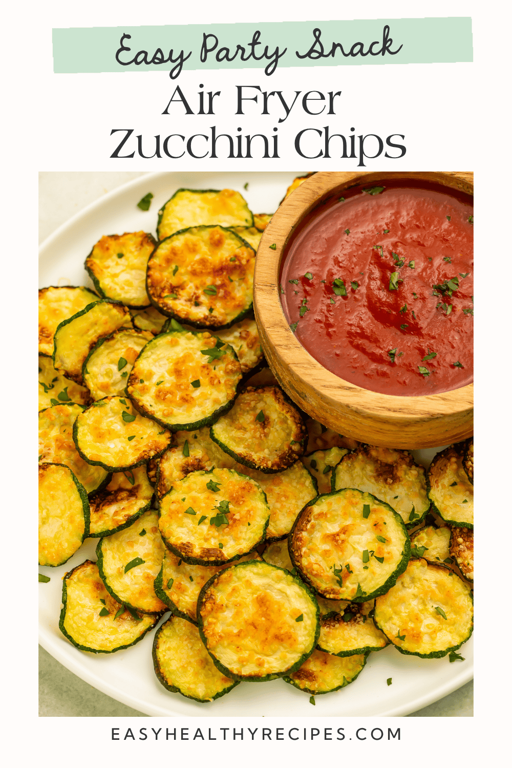 Golden air fryer zucchini chips served with marinara sauce for dipping.