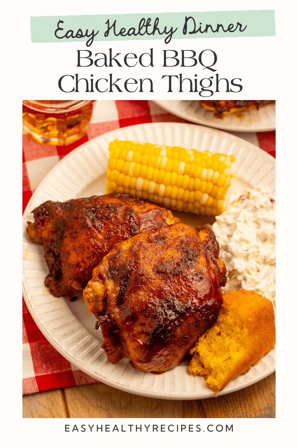 Baked BBQ chicken thighs served with potato salad, corn on the cob, and cornbread.