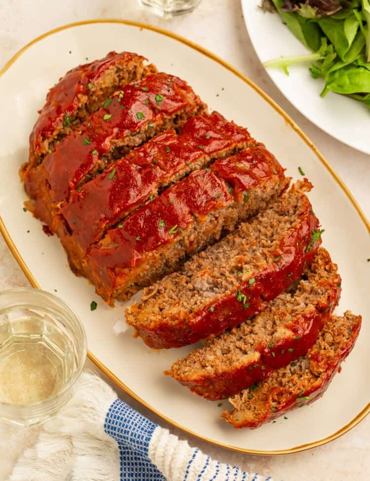 Platter of sliced healthy meatloaf topped with a rich tomato glaze and garnished with fresh parsley.