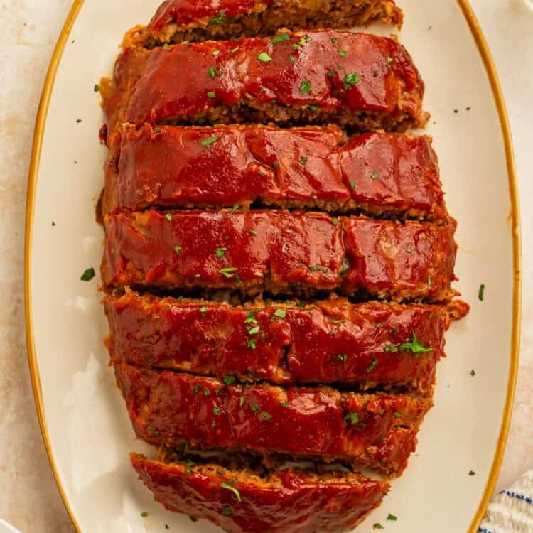 Overhead view of sliced healthy meatloaf covered in a glossy tomato glaze on a serving platter