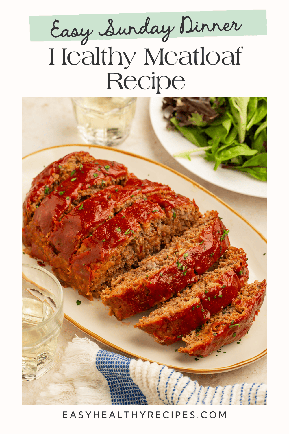 Sliced healthy meatloaf with a glossy tomato glaze served with a fresh green salad