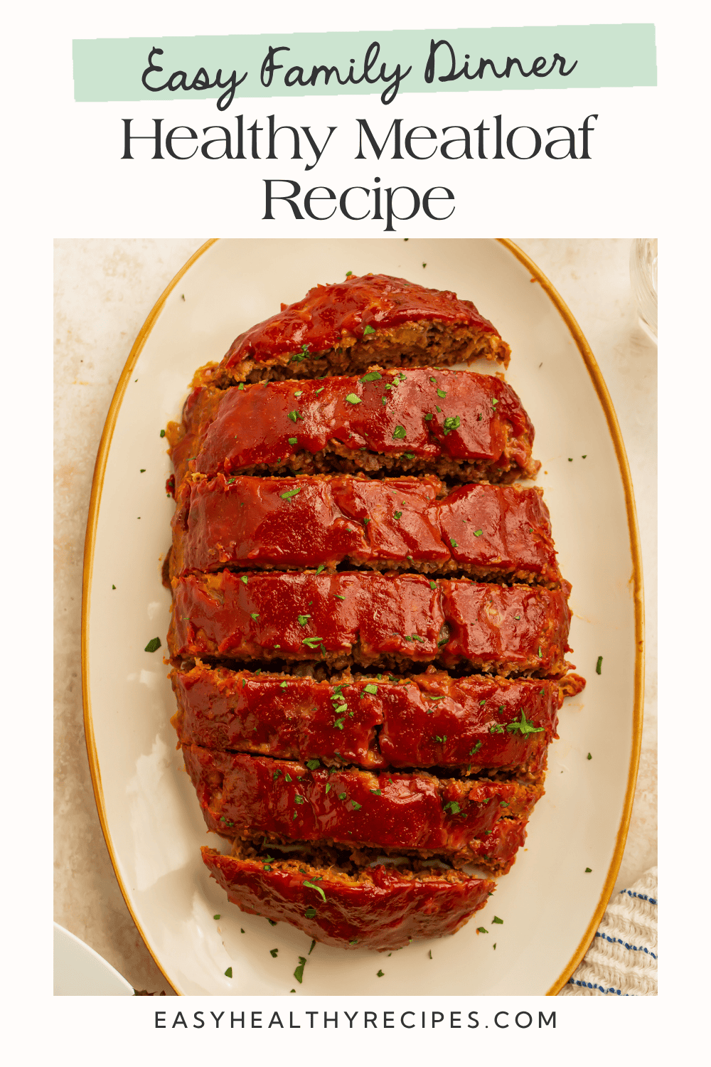 An overhead view of sliced healthy meatloaf coated in a rich tomato glaze on a serving platter