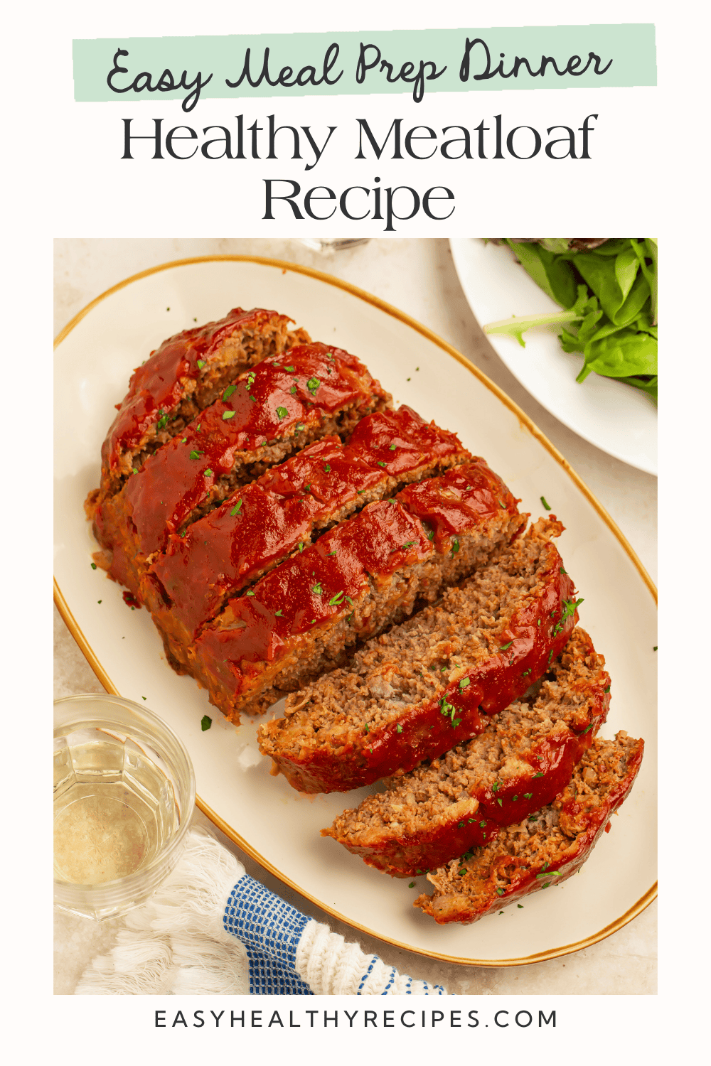 Sliced healthy meatloaf with tomato glaze served on a platter with a side salad