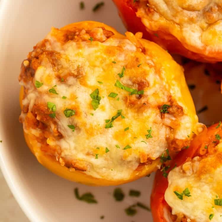 Overhead view of baked stuffed bell peppers filled with a savory turkey and rice mixture, topped with melted golden cheese and fresh parsley in a white baking dish