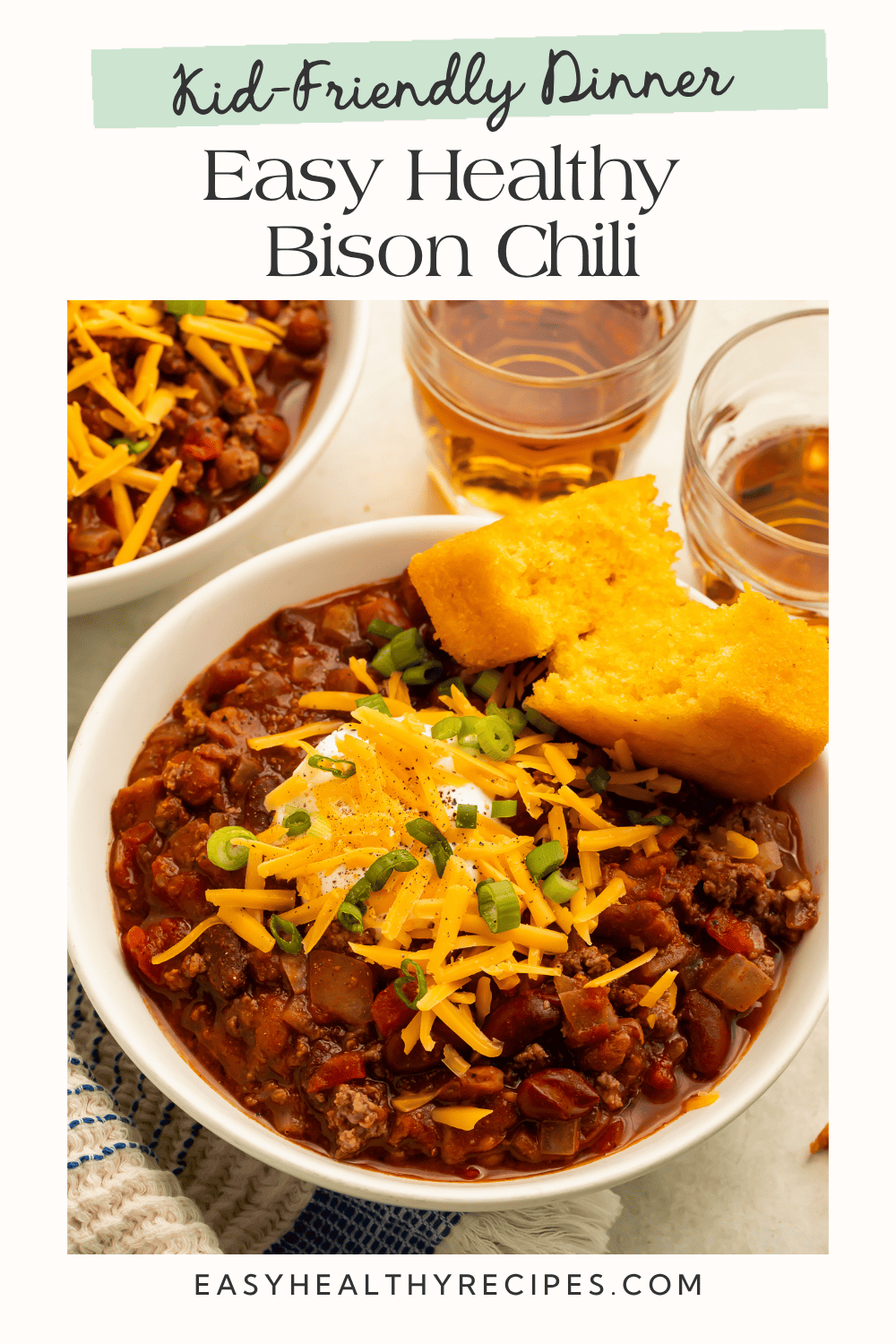 Kid-friendly dinner graphic with ground bison chili, shredded cheddar, sour cream, green onions, and cornbread.