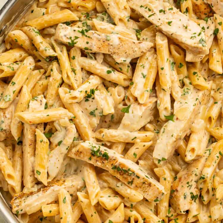 Garlic parmesan chicken pasta with sliced chicken, creamy penne, and parsley.
