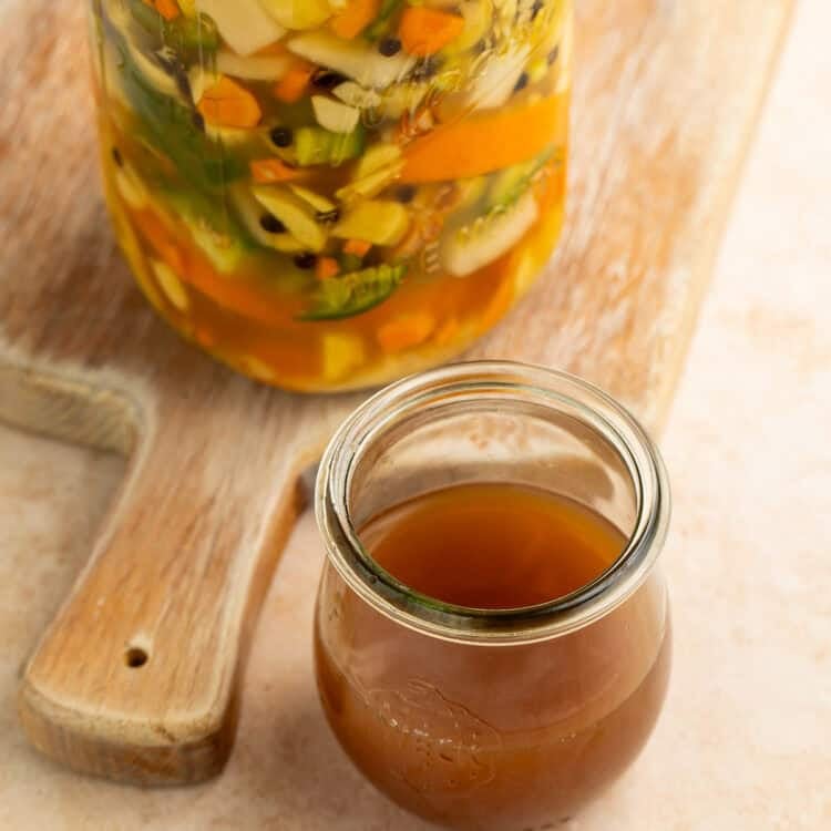 Homemade fire cider ingredients infusing in apple cider vinegar in a glass Mason jar