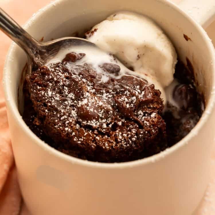 Spoonful of fudgy gluten-free chocolate mug cake with melting vanilla ice cream and chocolate chips