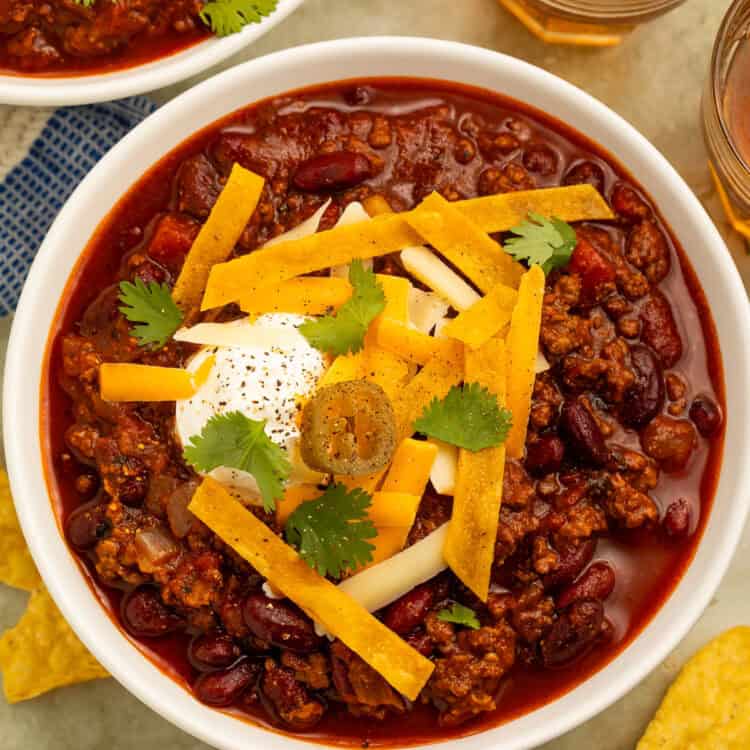Mexican chili with ground beef and kidney beans topped with cheese, sour cream, tortilla strips, cilantro, and jalapeños.