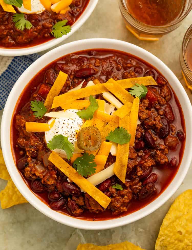 Mexican chili with ground beef and kidney beans topped with cheese, sour cream, tortilla strips, cilantro, and jalapeños.